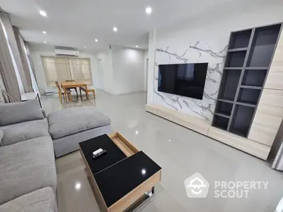 Modern living room with sleek furniture and large TV, perfect for relaxation and entertainment.