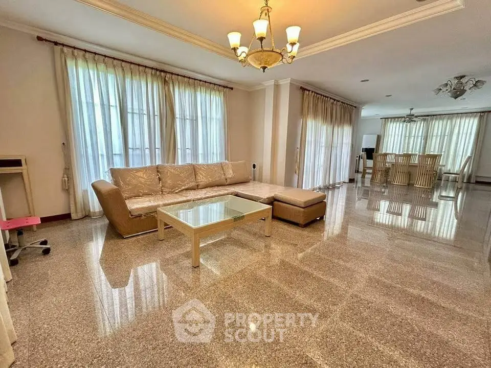 Spacious living room with elegant chandelier and large windows for natural light.