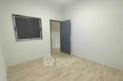 Spacious empty room with wooden flooring and a window, perfect for customization.
