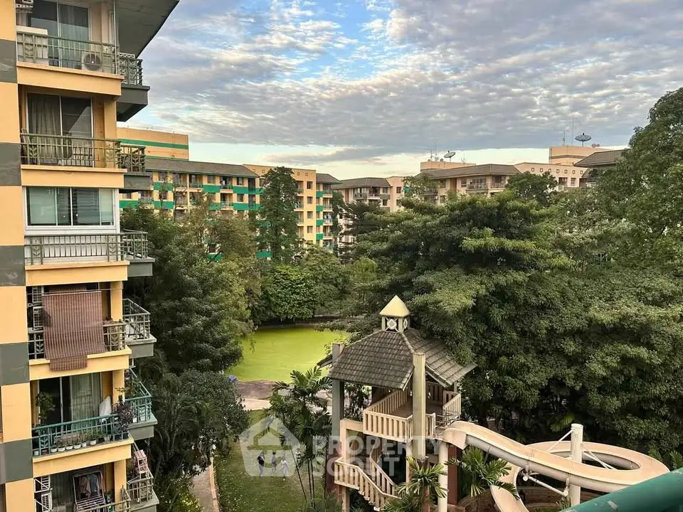 Scenic view of residential buildings with lush greenery and a water slide in a serene setting.