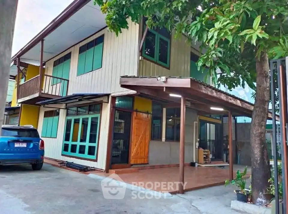 Charming two-story house with carport and lush greenery, perfect for family living.