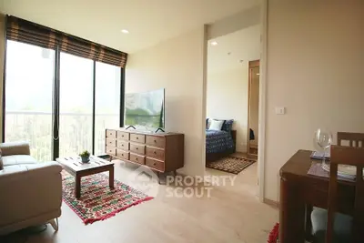 Modern living room with natural light and stylish decor, featuring a cozy seating area and a glimpse into a bedroom.