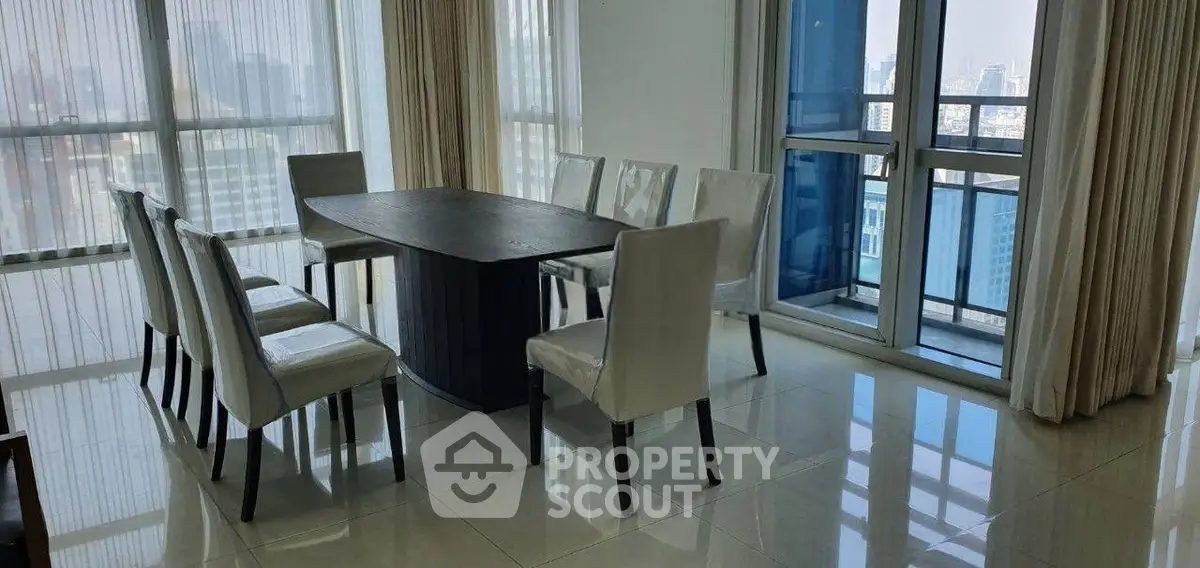 Spacious dining area with elegant table and chairs, featuring floor-to-ceiling windows and city views.