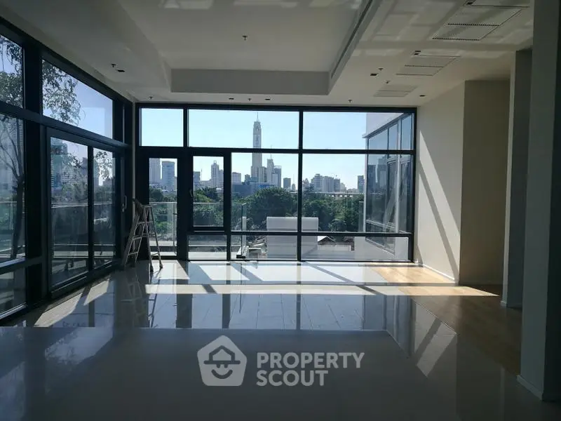 Spacious modern living room with floor-to-ceiling windows and stunning city skyline view.