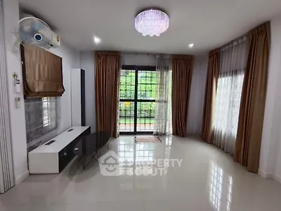 Spacious living room with elegant chandelier and large windows for natural light.