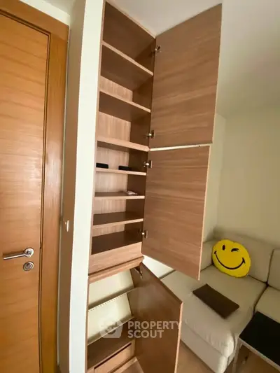 Spacious wooden storage cabinet in modern living room with cozy sofa and smiley face cushion.