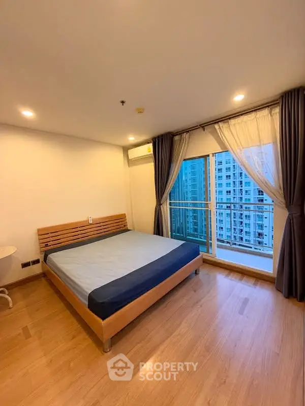Spacious bedroom with large window and city view in modern apartment