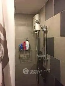 Compact bathroom shower area with modern tiles and showerhead