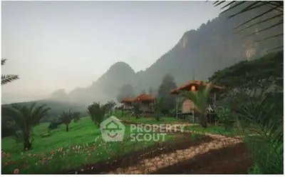 Scenic view of rustic cabins nestled in lush green landscape with mountain backdrop.