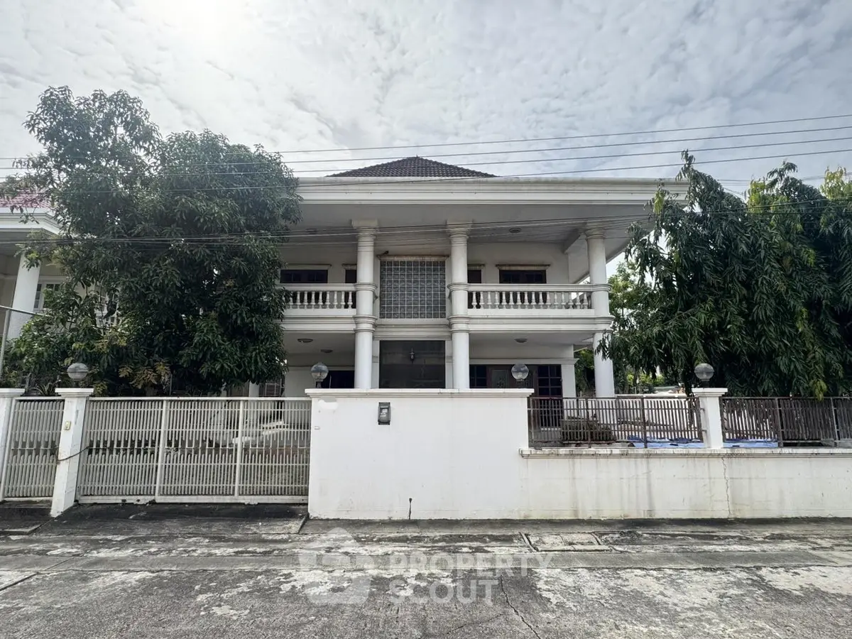 Stunning two-story white villa with lush greenery and elegant columns