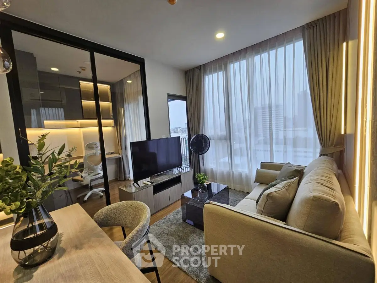 Modern living room with cozy sofa, large TV, and city view through floor-to-ceiling windows.