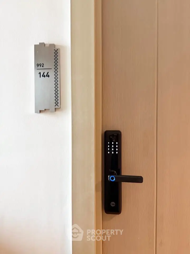 Modern apartment door with digital lock and room number signage, showcasing secure living.