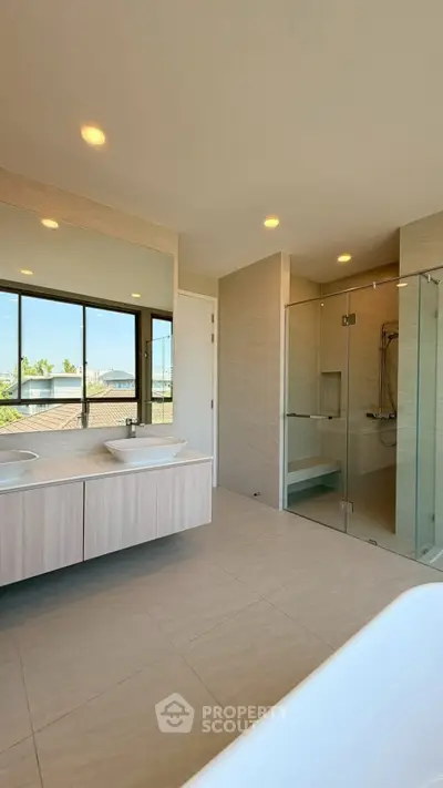 Luxurious modern bathroom with dual sinks, glass shower, and large mirror reflecting natural light.