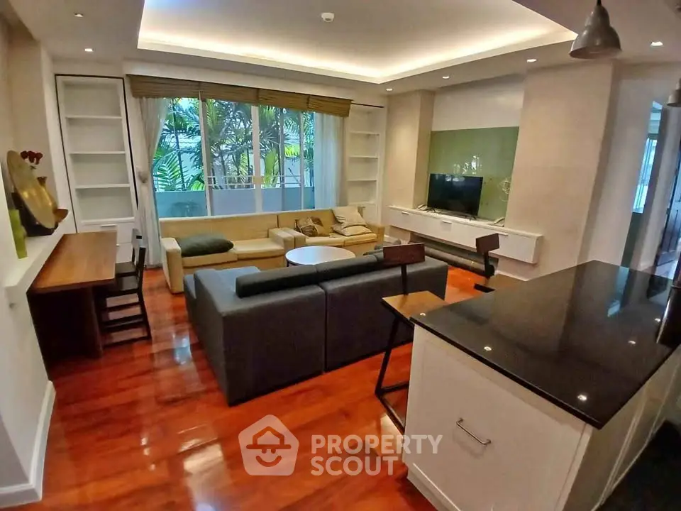 Spacious living room with modern decor and garden view, featuring hardwood floors and cozy seating area.