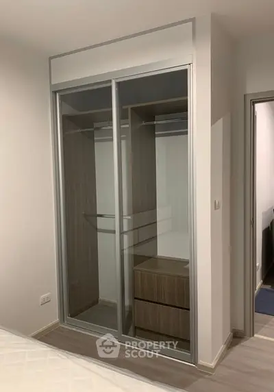 Modern bedroom with sleek built-in wardrobe featuring sliding glass doors and ample storage space.