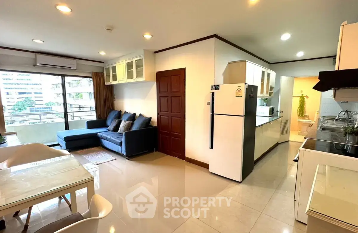 Spacious open-plan living room with modern kitchen and balcony view in urban apartment.