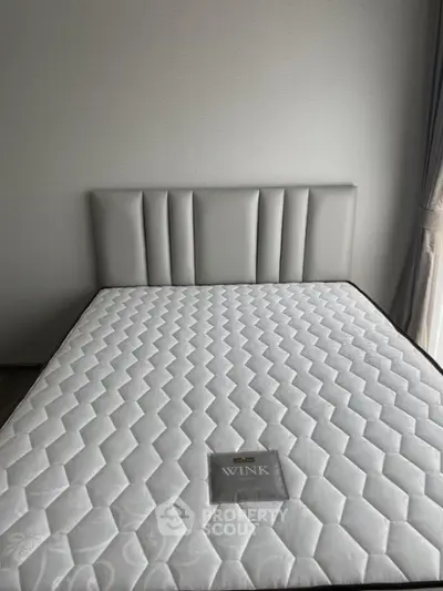Modern bedroom with stylish headboard and comfortable mattress in a well-lit room.