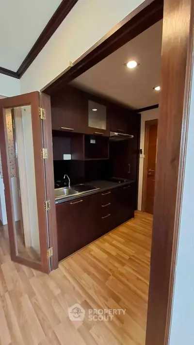 Compact kitchen with wooden cabinets and modern appliances in cozy apartment