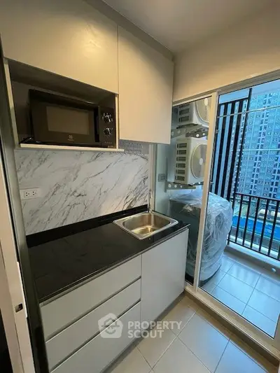 Modern compact kitchen with sleek cabinetry and balcony view