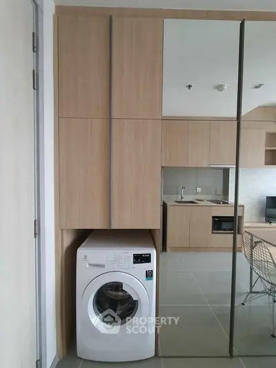 Modern apartment interior with built-in washing machine and sleek kitchen design.