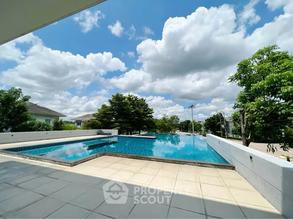 Stunning outdoor pool with clear blue water and lush greenery under a bright sky.