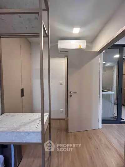 Modern interior with wooden flooring and sleek design, featuring a built-in wardrobe and air conditioning.
