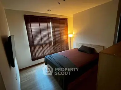 Cozy bedroom with warm lighting and wooden blinds, perfect for relaxation.