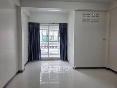 Spacious unfurnished room with large window and balcony access in modern apartment.