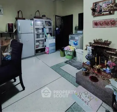 Cozy kitchen with fridge, washing machine, and traditional decor in a compact layout.