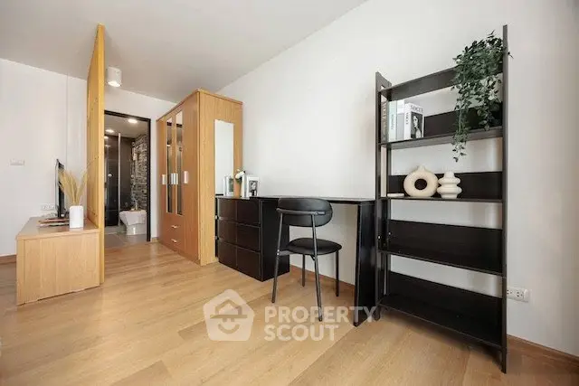 Modern study area with sleek black desk and shelving, adjacent to a stylish bedroom with wooden flooring.