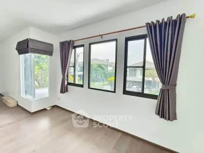 Bright and spacious room with large windows and elegant curtains, offering a serene view of the neighborhood.