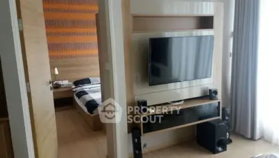 Modern apartment interior with TV and bedroom view, featuring stylish decor and natural lighting.