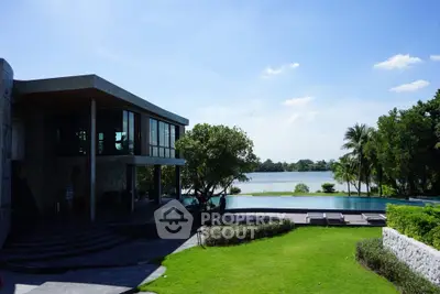 Luxurious lakeside property with modern architecture and lush green lawn, offering serene water views.