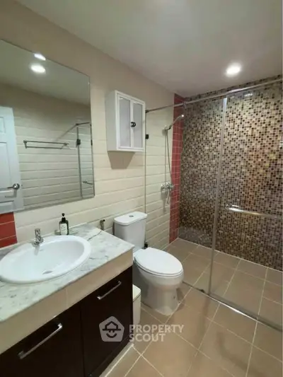 Modern bathroom with glass shower and stylish vanity in contemporary apartment.