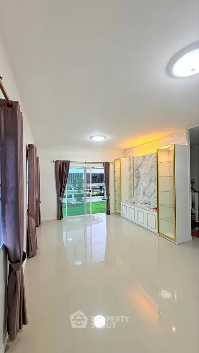Spacious living room with elegant marble feature wall and large windows offering natural light.