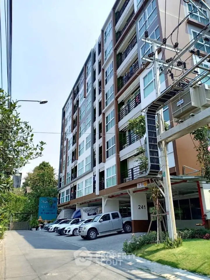 Modern multi-story apartment building with parking and lush greenery, ideal urban living.