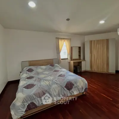 Spacious bedroom with wooden flooring and modern furniture in a cozy apartment.