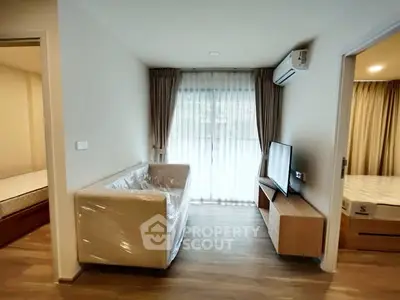 Modern living room with natural light, featuring a cozy sofa and sleek TV setup.