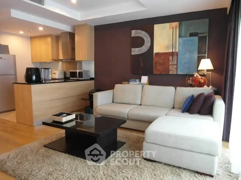 Modern living room with open kitchen, stylish decor, and cozy seating area.