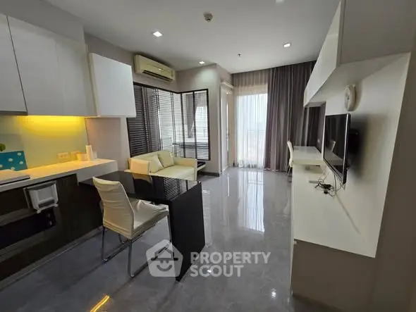 Modern living room with sleek furniture and open layout, featuring a cozy seating area and large windows.