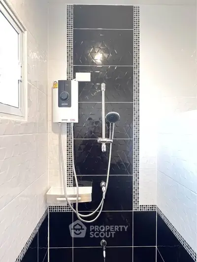 Modern bathroom with sleek black and white tiles and a wall-mounted shower heater.