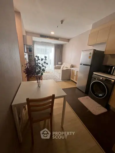 Cozy studio apartment with modern kitchen and living area, featuring a washing machine and fridge.