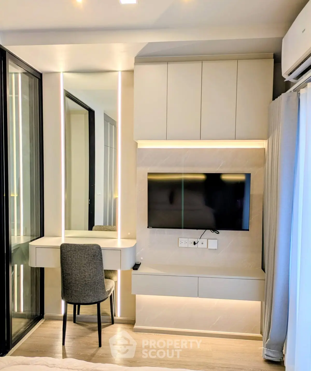 Modern bedroom with sleek built-in TV unit and stylish vanity area, featuring elegant lighting and contemporary design.