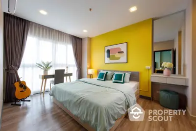 Bright and inviting bedroom with a large window, hardwood floors, and vibrant yellow accent wall, complemented by modern furnishings and a cozy workspace.