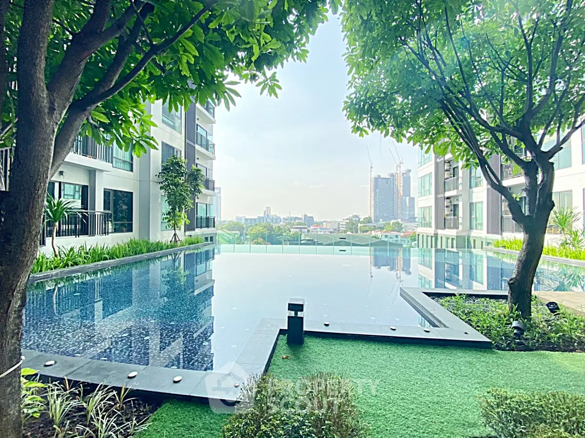 Luxurious apartment complex with stunning pool and lush greenery, offering a serene urban oasis.