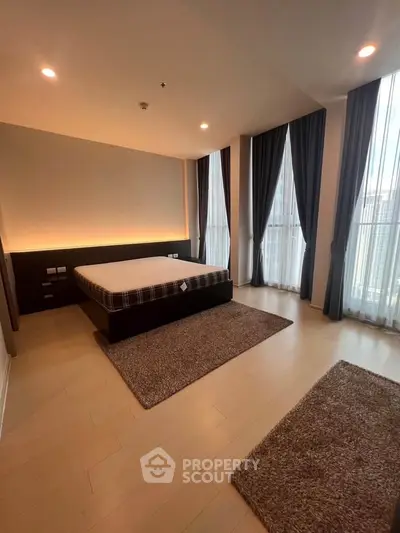 Spacious bedroom with large windows and elegant curtains in modern apartment