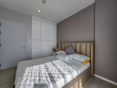 Modern bedroom with stylish decor and ample natural light, featuring a comfortable bed and built-in wardrobe.
