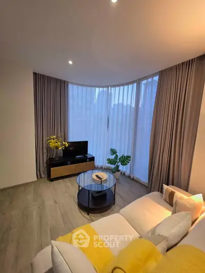 Modern living room with large windows, cozy sofa, and stylish decor in a contemporary apartment.