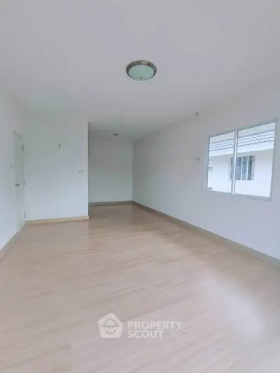 Spacious empty room with wooden flooring and natural light, ideal for customization.
