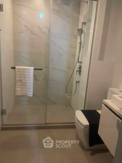 Modern bathroom with glass shower and sleek fixtures in luxury apartment.
